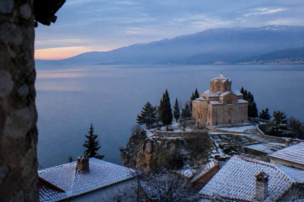 Snow dusting the roofs of Ohrid old town and the church of St John at Kaneo above a calm lake