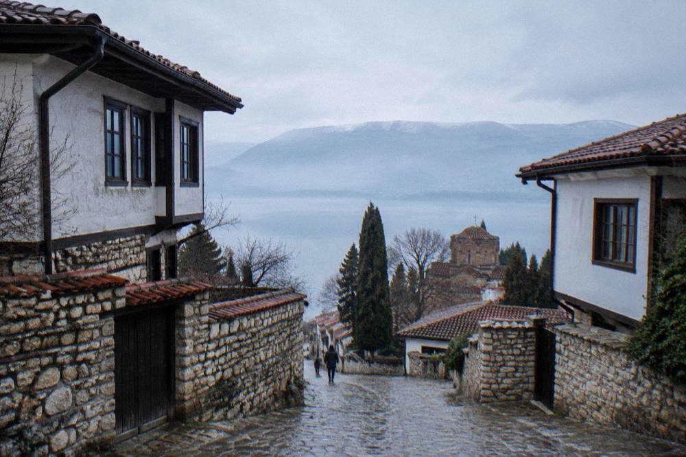 Calm morning water on Lake Ohrid with mist over the surface and hills beyond