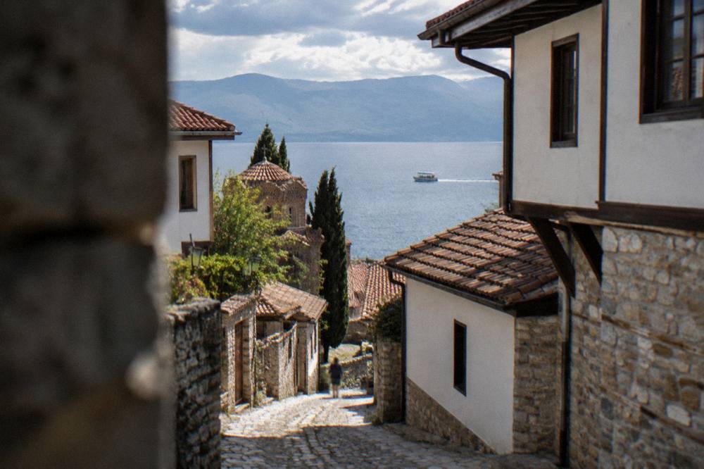 A small boat crossing open water toward distant mountains on Lake Ohrid