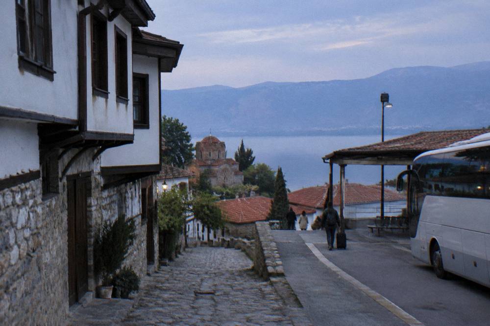 An intercity bus parked at a small station platform in a Balkan town