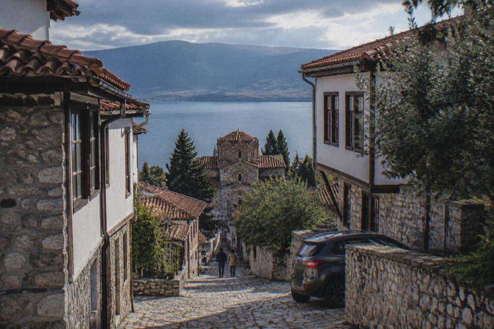 A car parked at a roadside viewpoint above a blue mountain lake