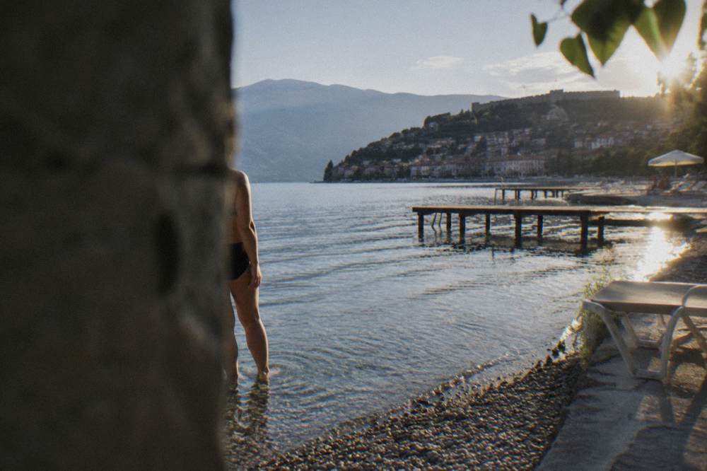 Feet standing on smooth pebbles in clear shallow lake water