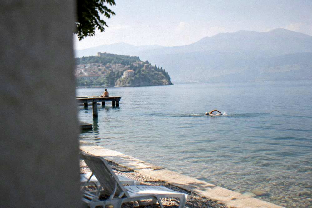 A swimmer in a cap doing front crawl across open lake water