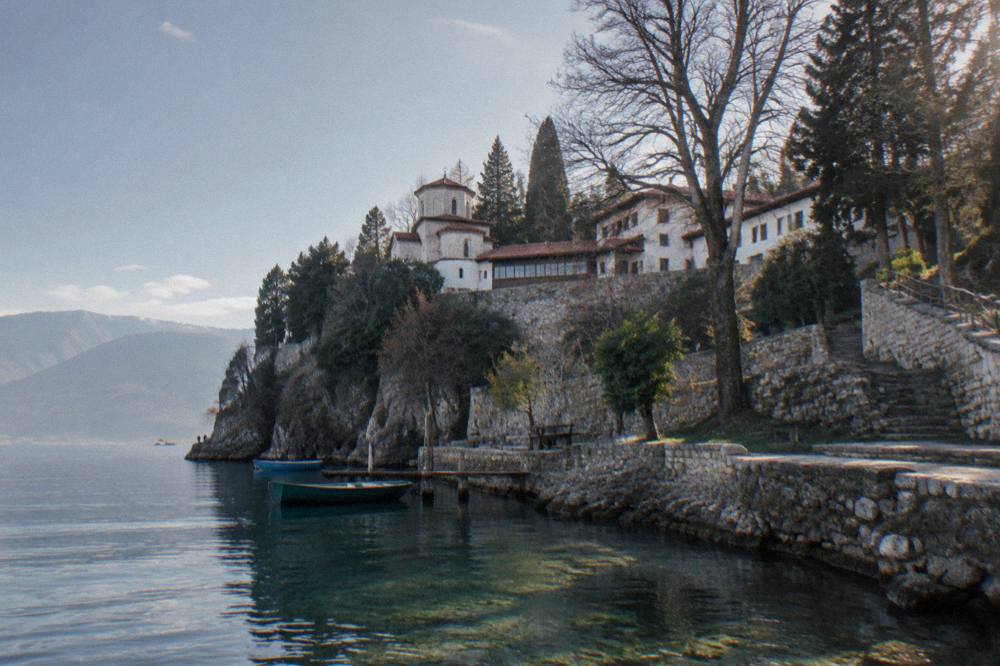 The white walls of St Naum monastery among trees at the edge of Lake Ohrid