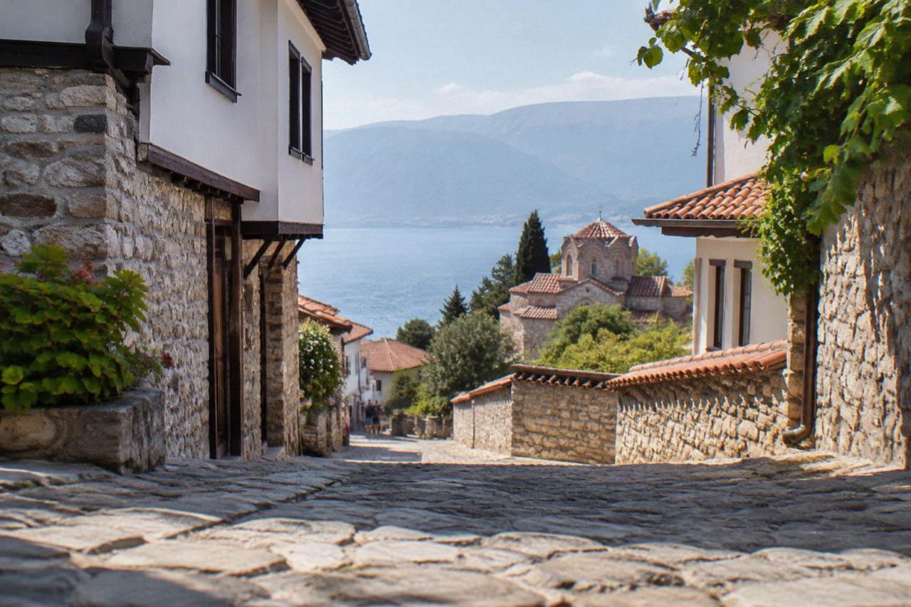 A lakeside town of red roofs climbing a hillside above a wide blue mountain lake