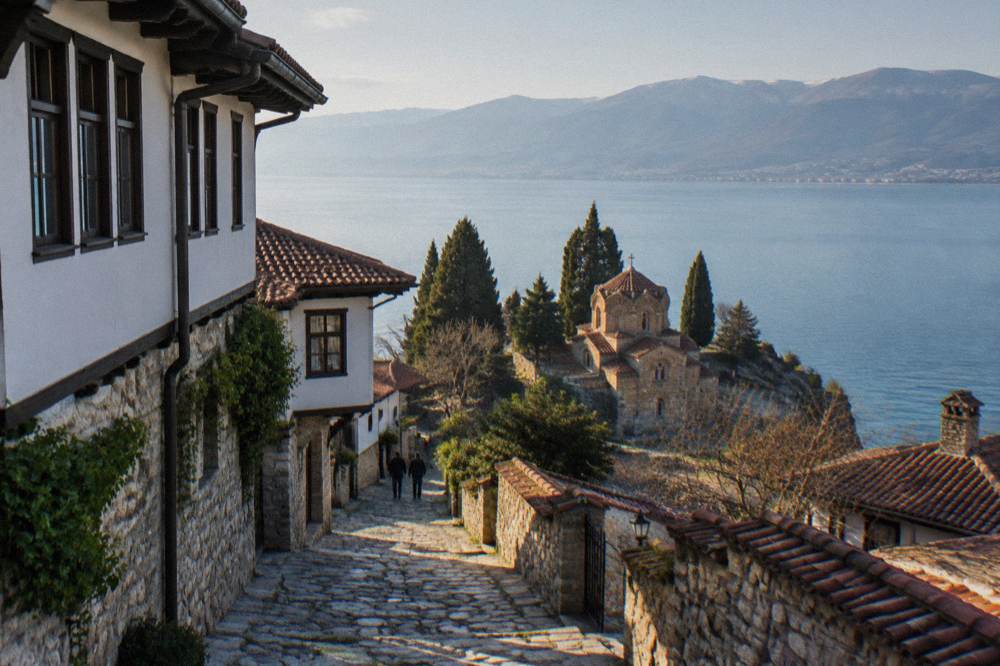 A small stone church on a cliff above a calm blue lake