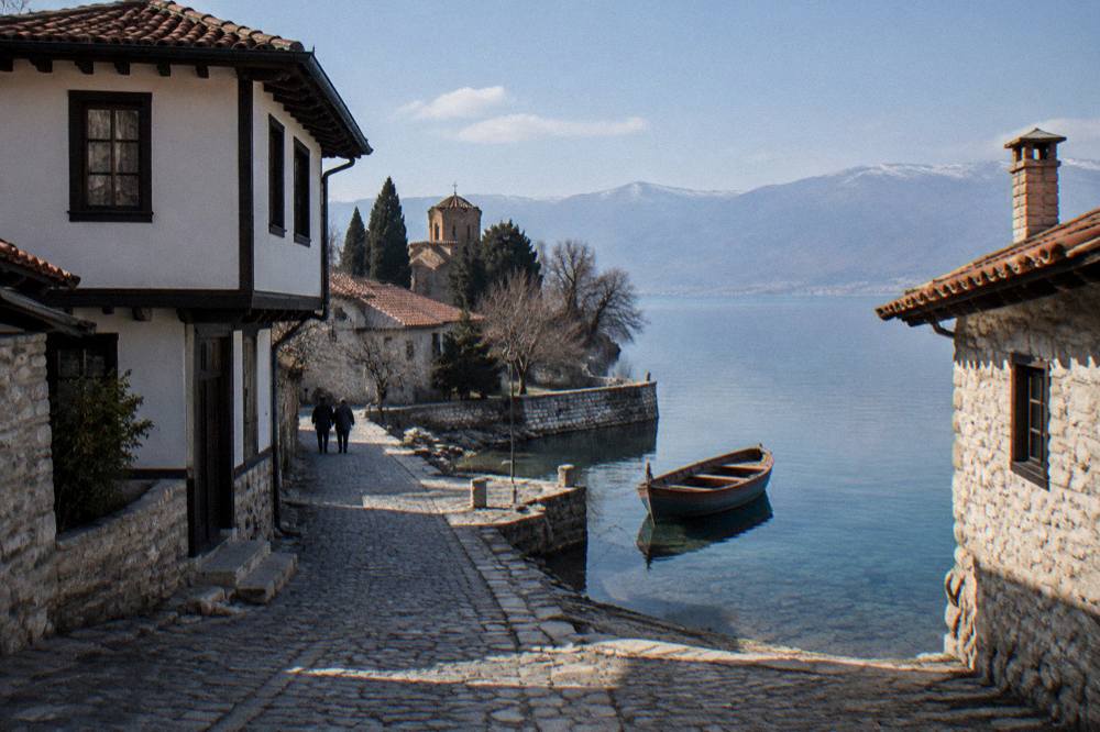 A wooden boat moored at a stone quay beside clear shallow lake water in the morning