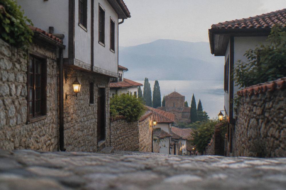 Lantern-lit stone lane in the Ohrid old town at night with warm light from windows