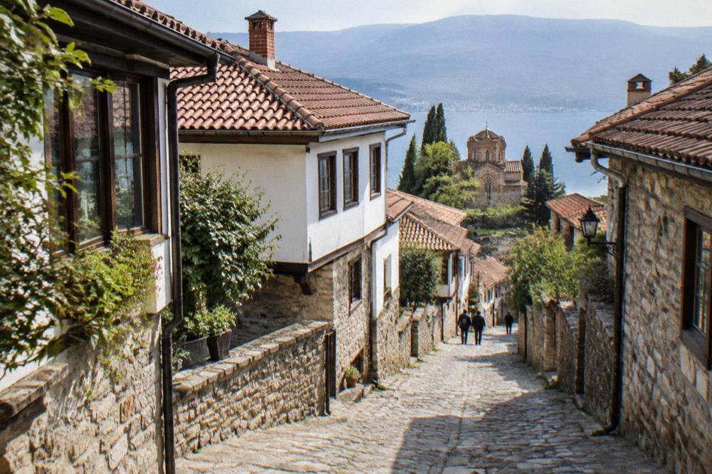 Old town street in Ohrid at night with stone walls lit by warm street lamps