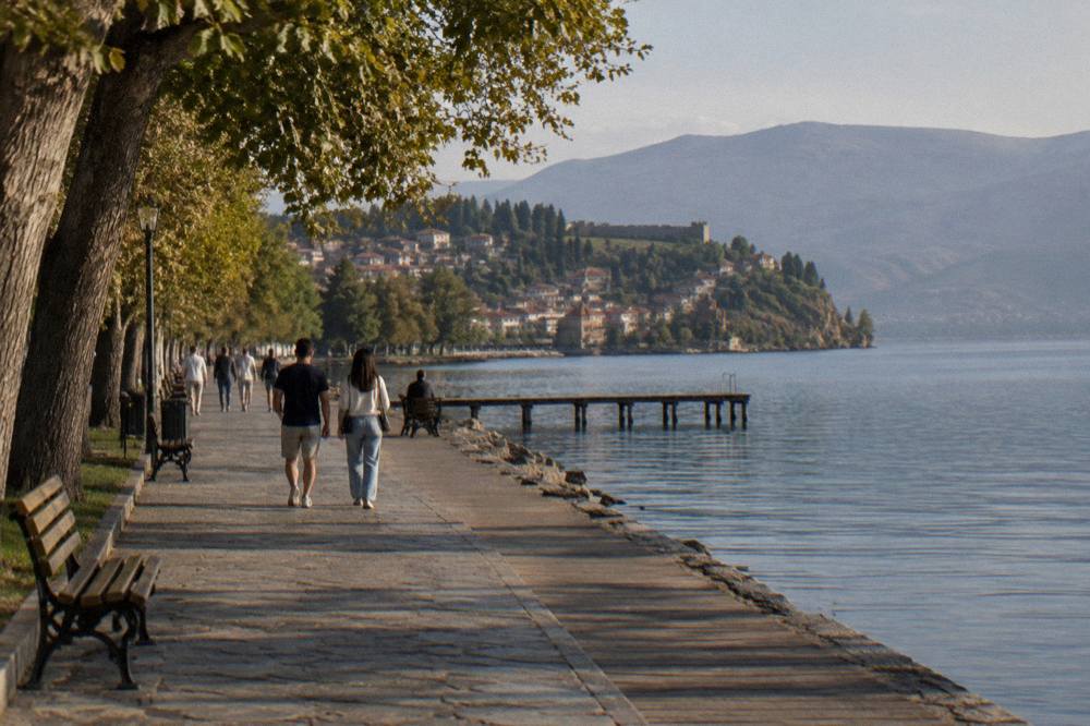People strolling along a lakeside promenade in Ohrid during a warm evening