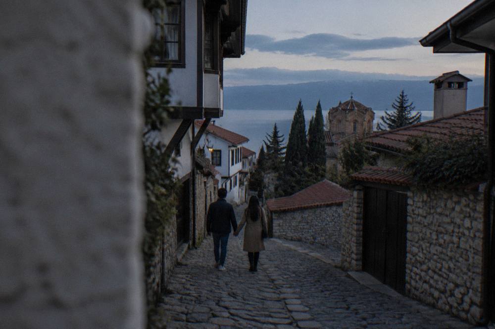 Two people walking hand in hand up a cobbled lane in Ohrid old town