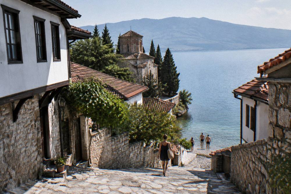 Swimmers entering clear water from a pebble shore on Lake Ohrid