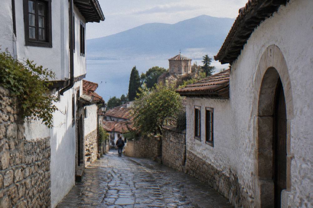 A narrow stone lane in Ohrid old town with whitewashed walls and an arched doorway