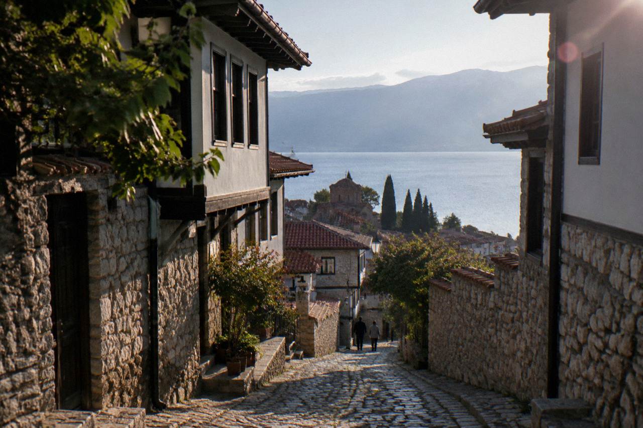 Stone lanes of Ohrid old town climbing toward a hilltop fortress above a blue lake
