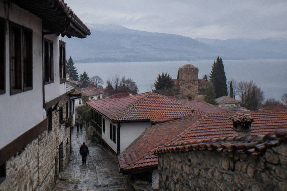 A quiet museum room in Ohrid with whitewashed stone walls and empty wooden display cases
