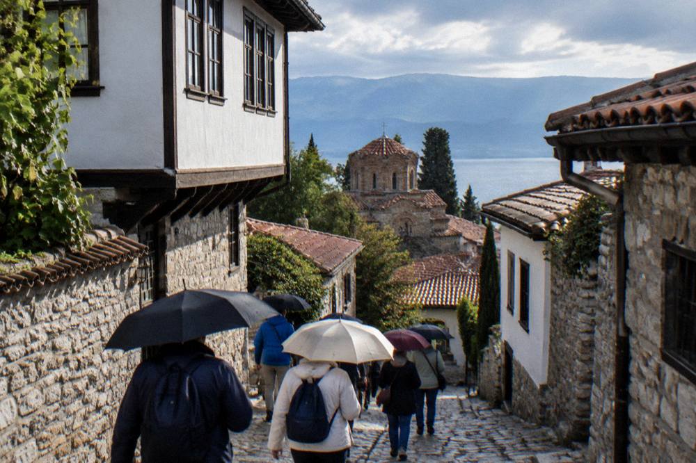 Guided walking group with umbrellas on a stone street in Ohrid old town