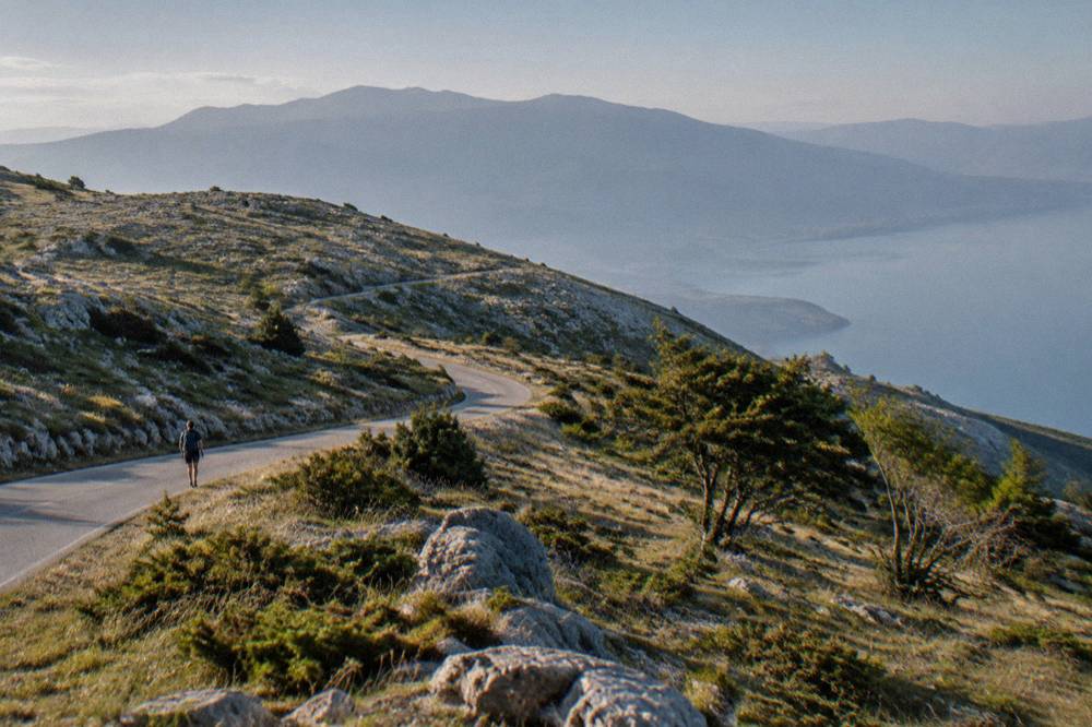 A mountain road winding through open grassland in Galicica National Park