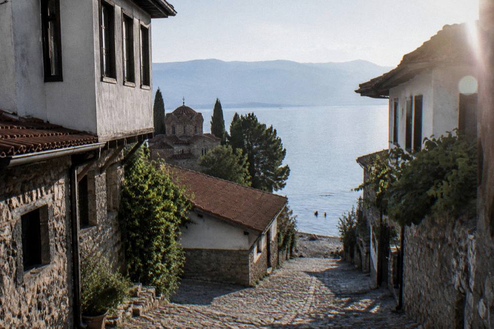 Swimmers in clear water beside a pebble beach on Lake Ohrid