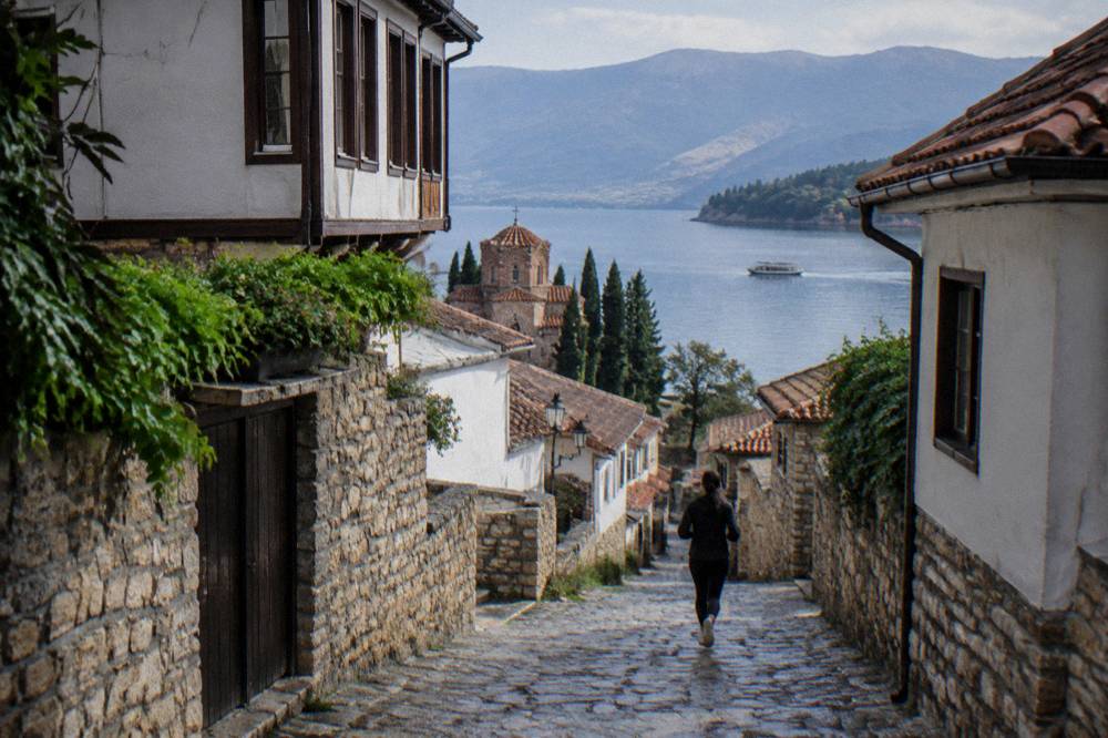 A boat crossing open water on Lake Ohrid toward forested hills