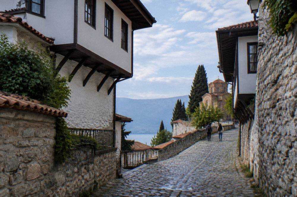 A stone lane in Ohrid old town climbing toward the fortress with whitewashed walls