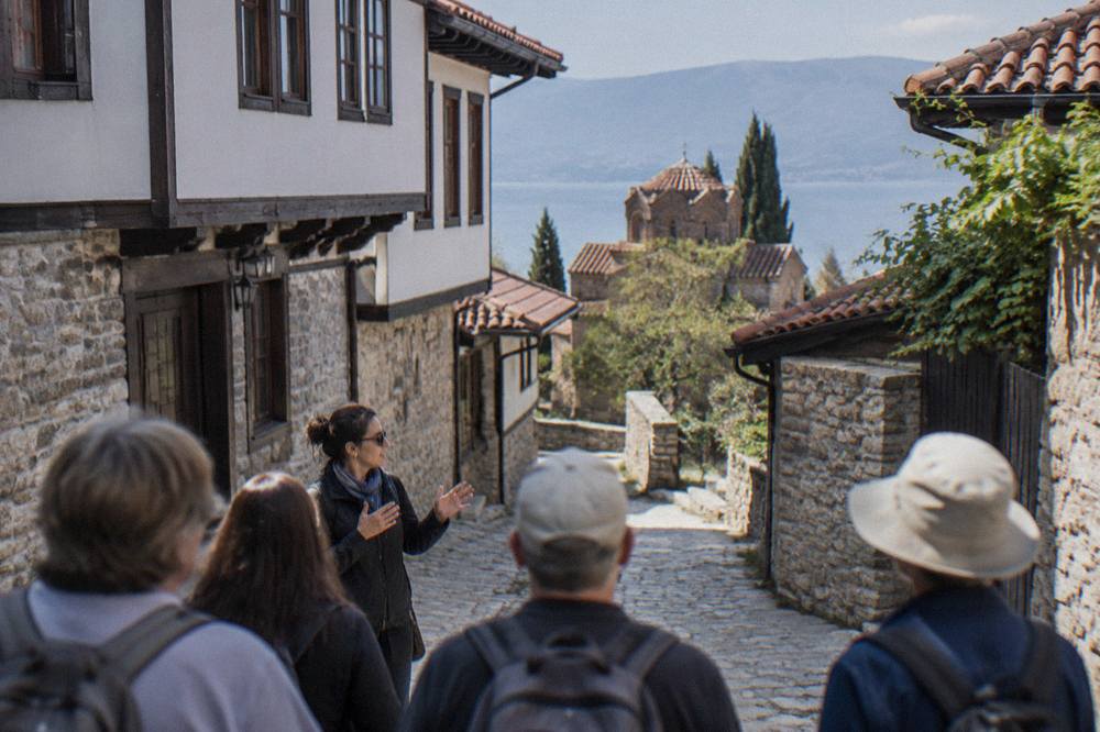 Guide speaking to a small group of visitors on a stone street in the Ohrid old town
