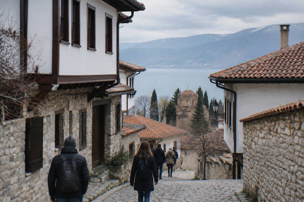 Visitors walking beside traditional stone houses with wooden upper floors in Ohrid