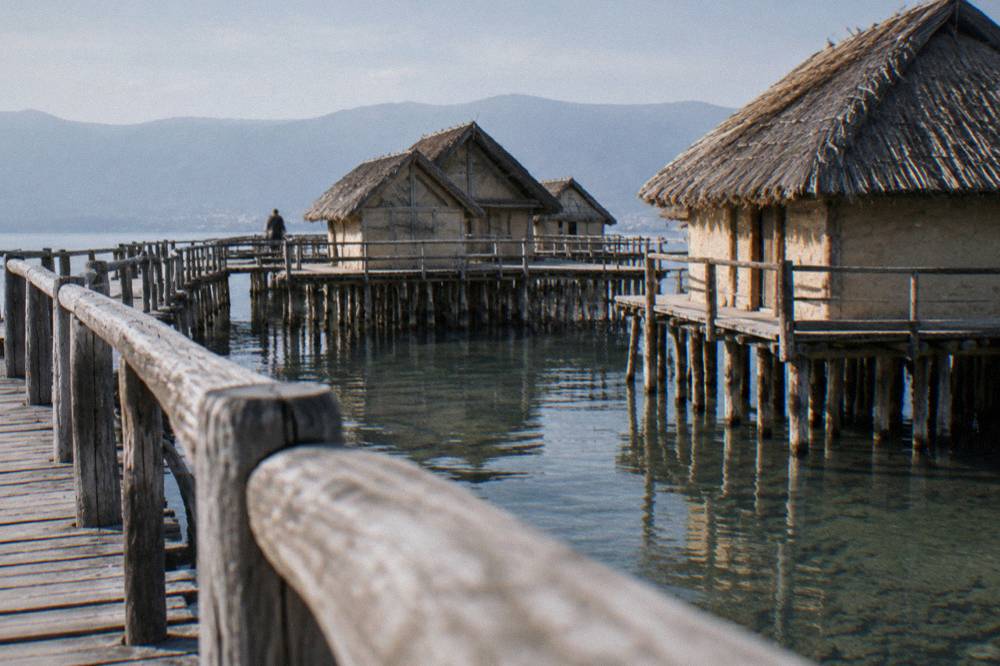 A reconstructed wooden pile-dwelling settlement standing on stilts above the water at the Bay of Bones on Lake Ohrid