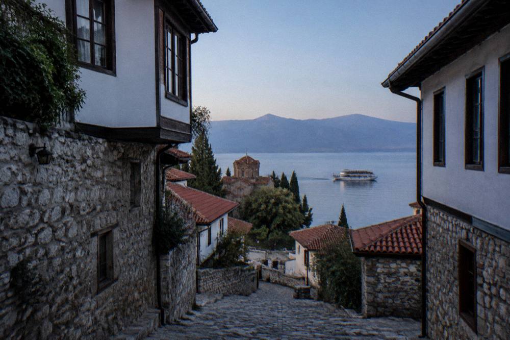A tour boat loaded with passengers heading south across open water on Lake Ohrid under a clear sky
