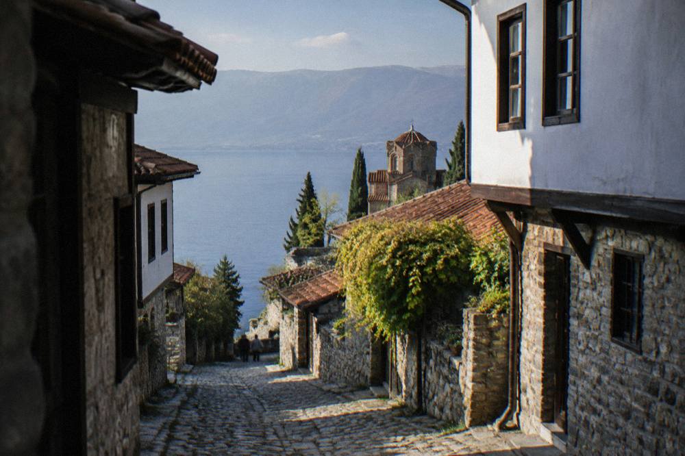 Calm blue water of Lake Ohrid seen from a boat deck with mountains rising on the far shore