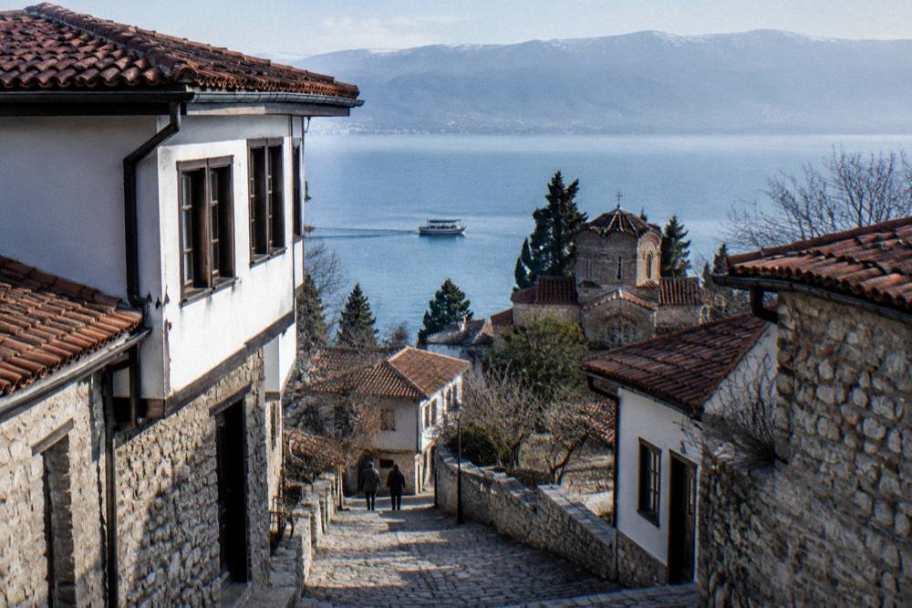 A small boat cruising along the Ohrid lake front below the old town churches