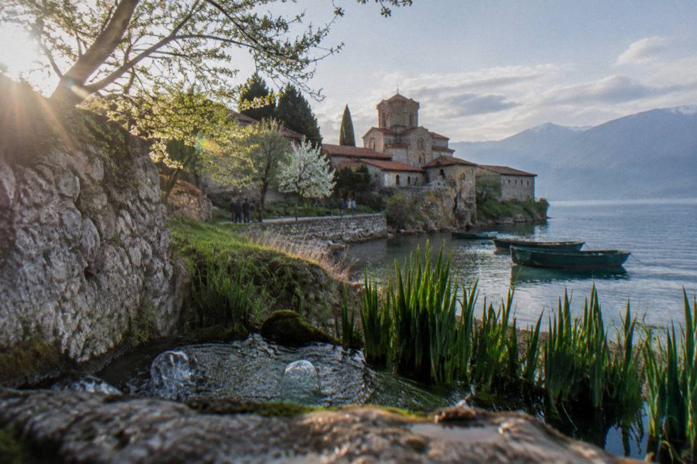 Clear spring water bubbling up among reeds beside a stone monastery wall