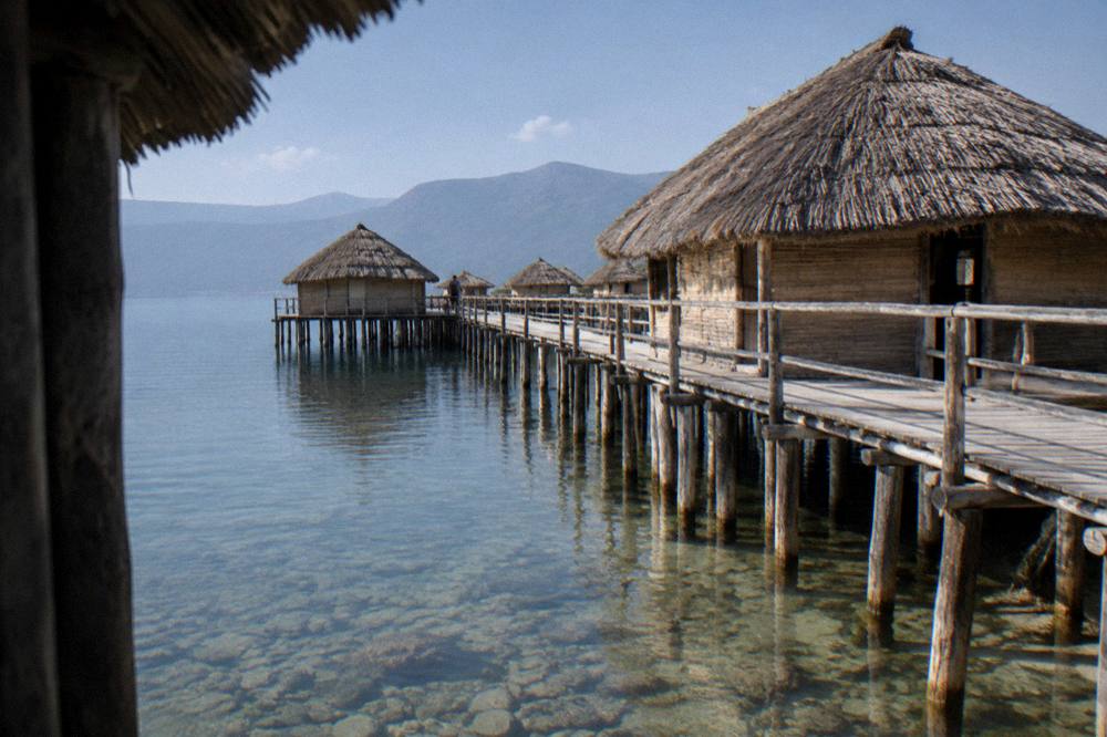 A reconstructed wooden pile dwelling standing on stilts over lake water