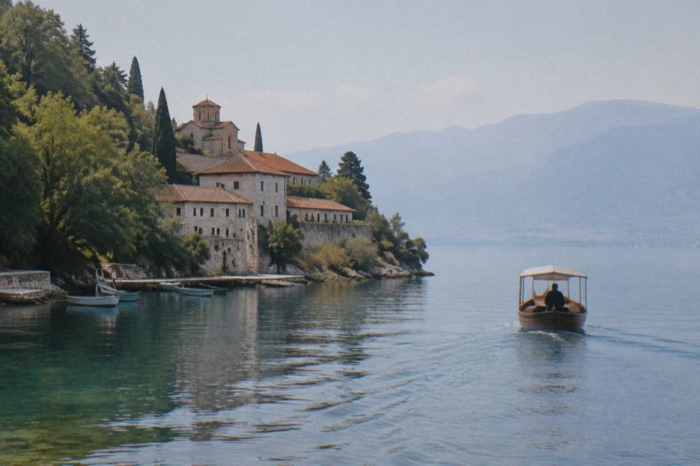 A wooden boat crossing wide open lake water toward distant mountains